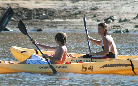 Two paddlers in yellow sit-on-top kayaks on the calm water near the beach at Collins Lake.